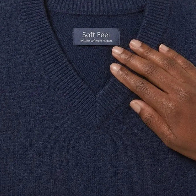 A well-worn navy school jumper folded on a child’s bed, fabric softened by many washes