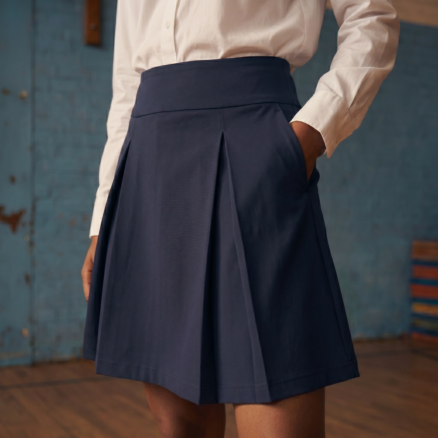 The Flydays skirt on a child mannequin, a hand lifting the pleats to show the built-in inner short